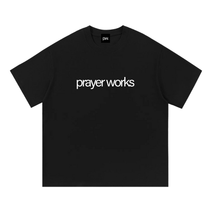 Black t-shirt with 'prayer works' text on a white background
