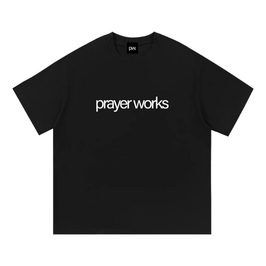 Black t-shirt with 'prayer works' text on a white background